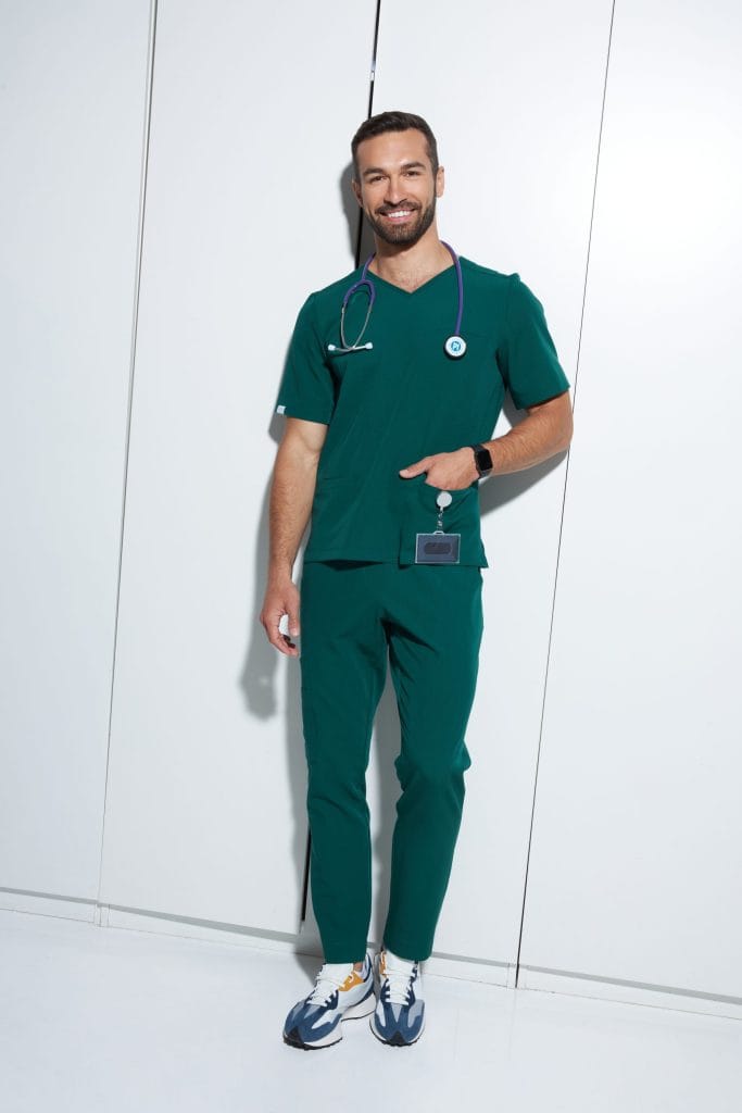 Mężczyzna w zielonym uniformie medycznym z stetoskopem i identyfikatorem.