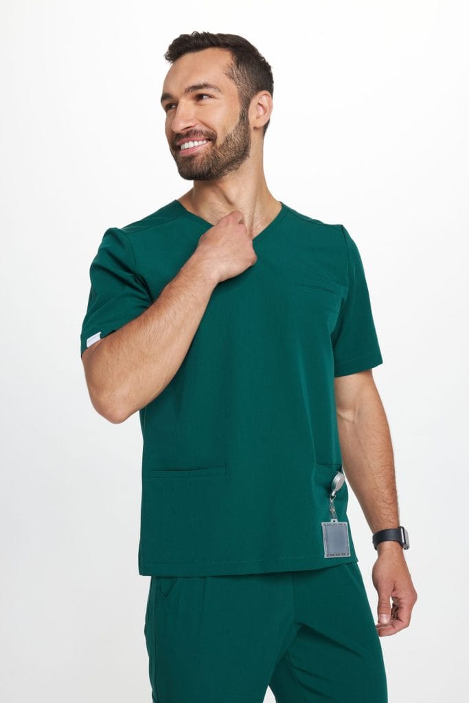 Mężczyzna w zielonym komplecie odzieży medycznej uśmiecha się i patrzy w bok.