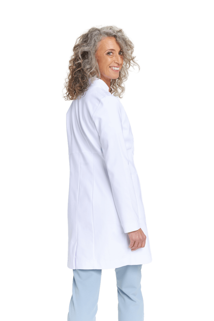 Kobieta w białym fartuchu medycznym uśmiecha się na tle neutralnym.