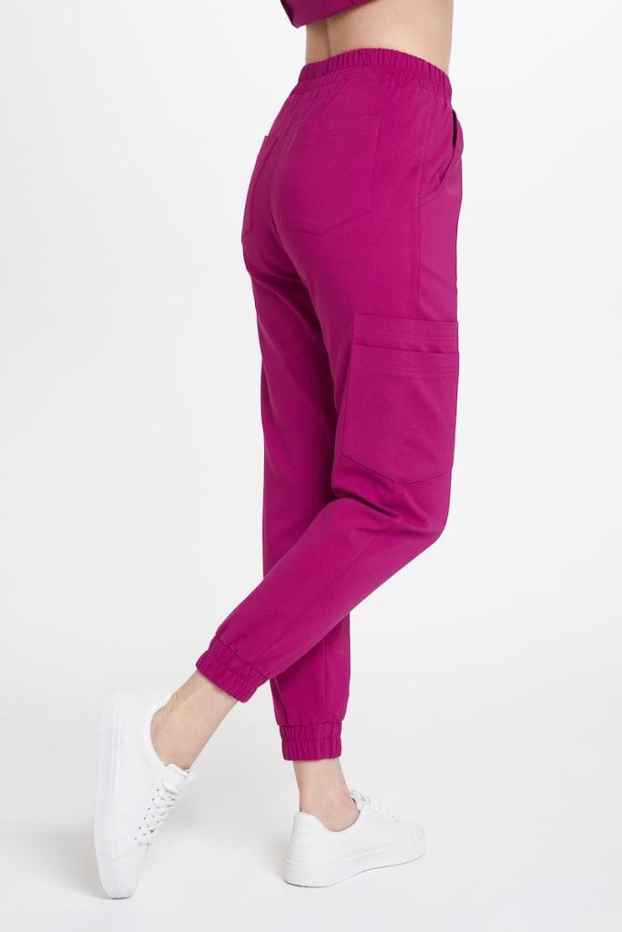 Damskie joggery medyczne w kolorze magenta z kieszeniami i elastycznymi zakończeniami nogawek.
