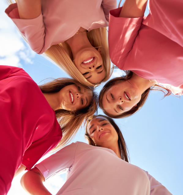 The photo shows four students wearing SCRUBS medical clothing from the BASIC collection.