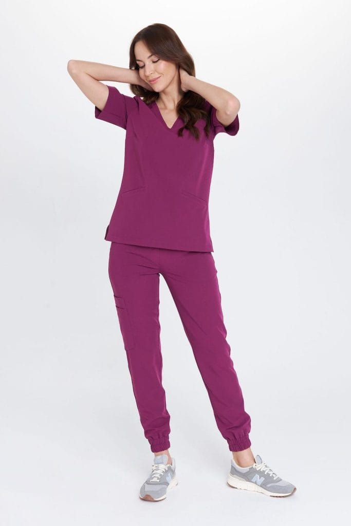 Kobieta w medycznej odzieży w kolorze śliwkowym, relaxująca z rękami za głową