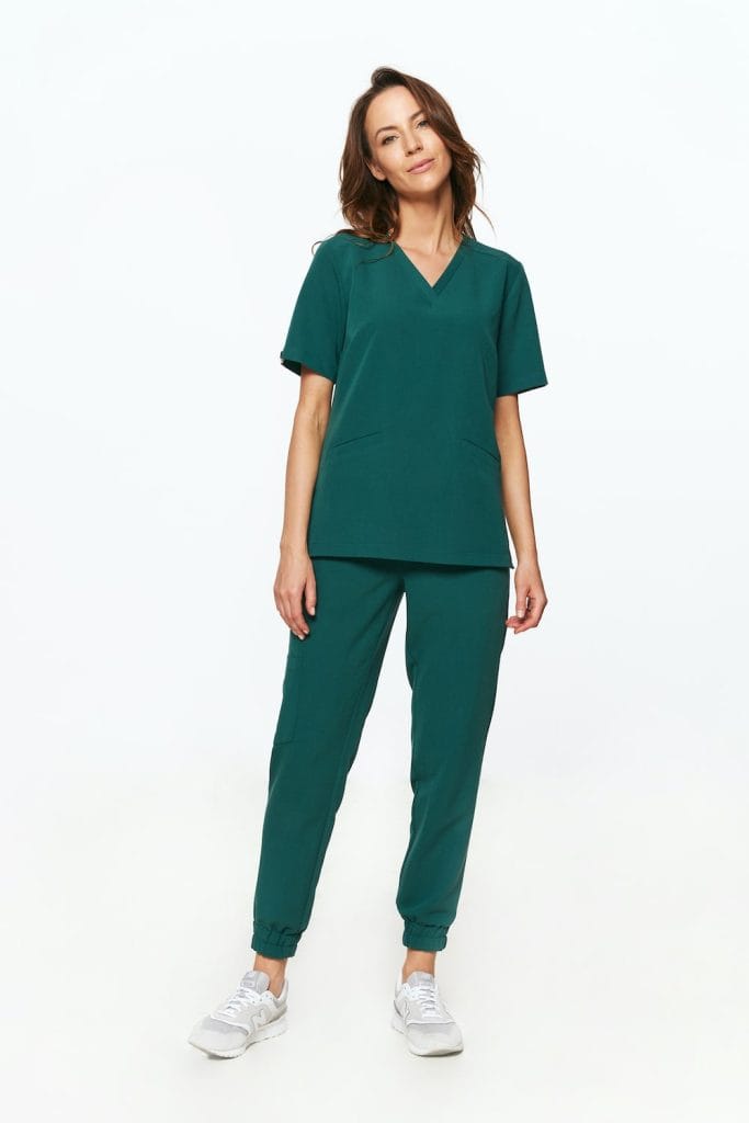 Kobieta w butelkowo zielonej damskiej bluzce medycznej scrubs i dopasowanych spodniach