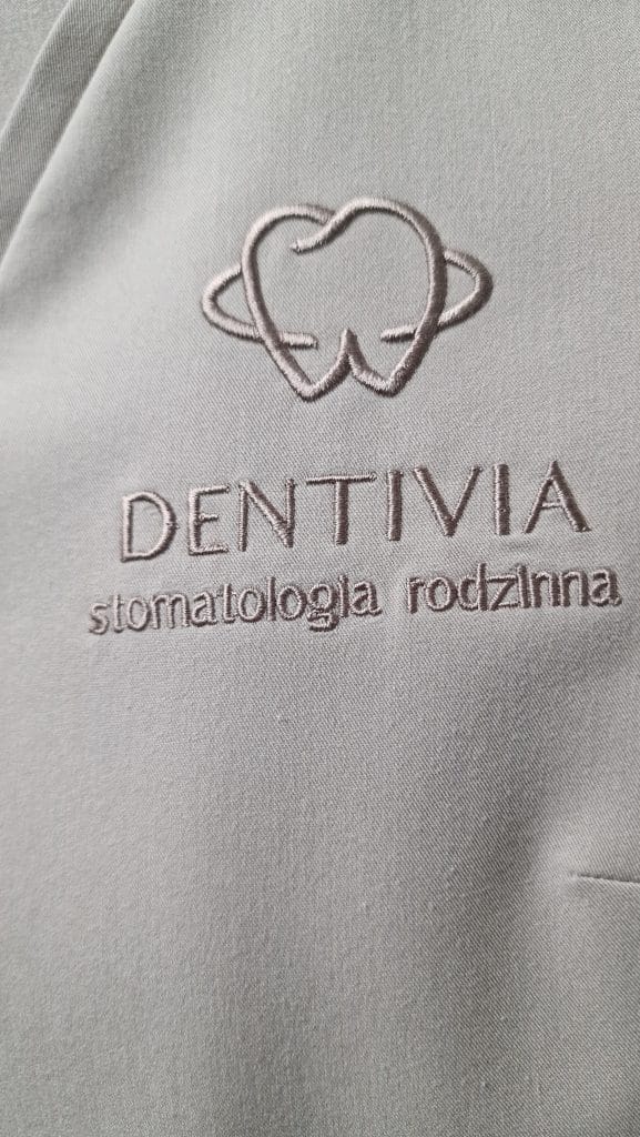 Logo kliniki stomatologicznej Dentivia wyhaftowane na medycznym ubraniu ochronnym.