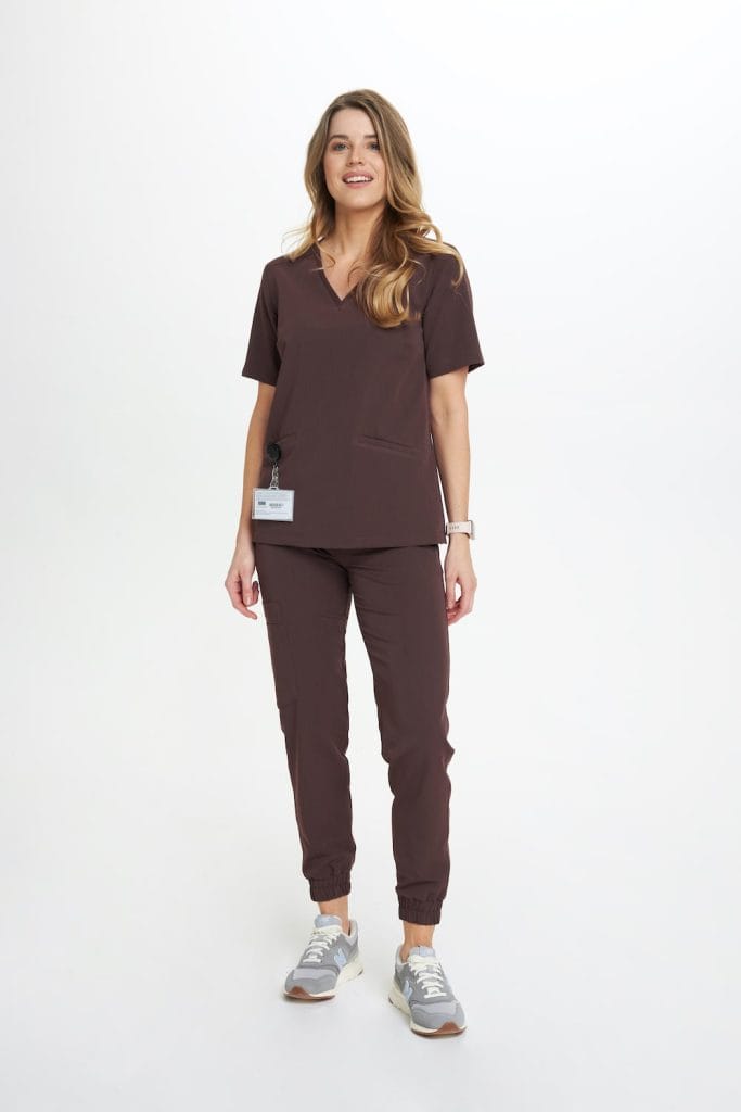 Modelka w brązowej bluzce medycznej damskiej scrubs Basic DARK CHOCOLATE i spodniach medycznych.