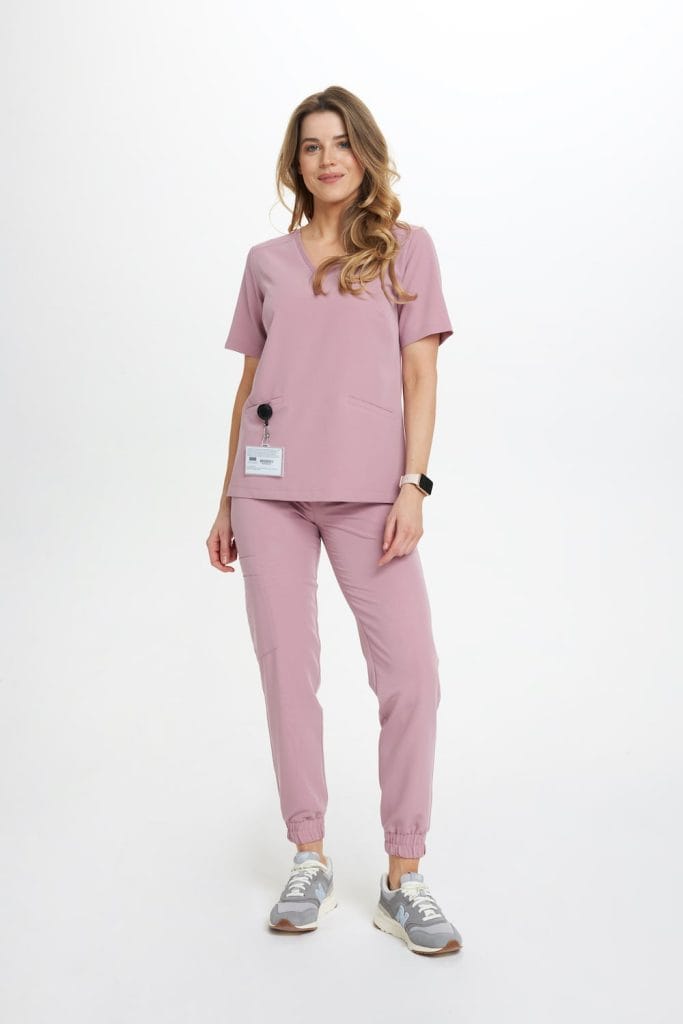 Kobieta w różowych spodniach medycznych typu joggery i dopasowanym topie.