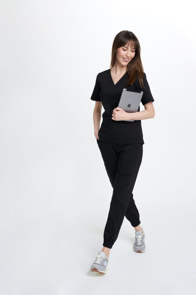 Kobieta w czarnych spodniach medycznych joggerach scrubs Basic z tabletem w ręku