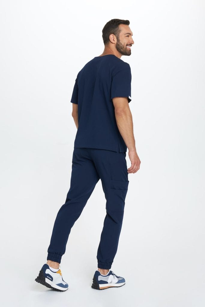 Mężczyzna w granatowych medycznych spodniach joggerach oraz granatowej bluzie medycznej.