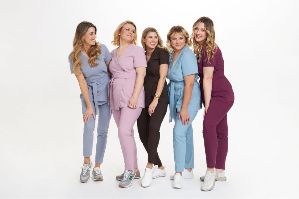 Pięć kobiet w kolorowej odzieży medycznej stoi razem na białym tle.