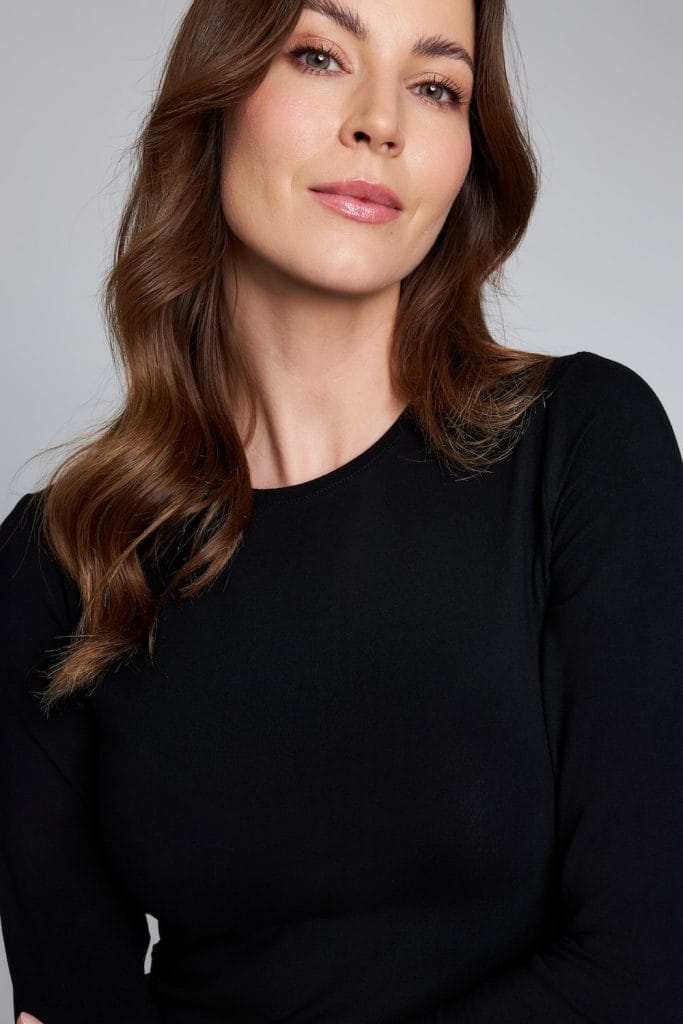 Kobieta w czarnym longsleeve medycznym damskim na jasnym tle.