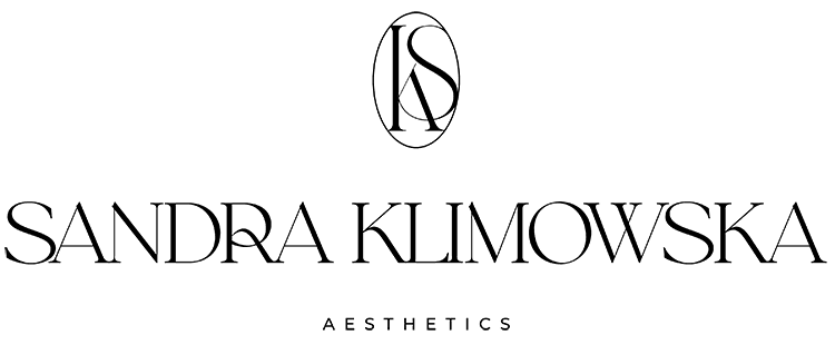 Kobieta w nowoczesnym drewnianym biurku z laptopem, kubkiem i rośliną, uśmiechnięta, ubrana w medyczny uniform.