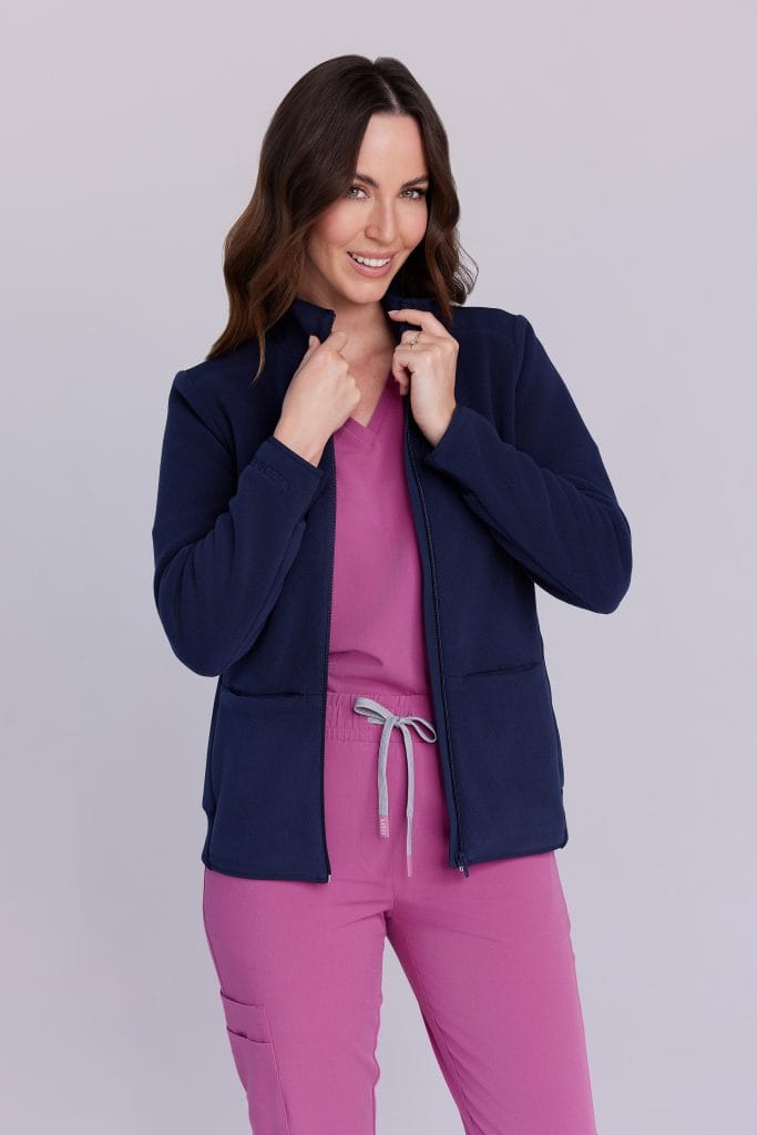 Kobieta w różowym stroju medycznym i granatowej bluzie na zamek.