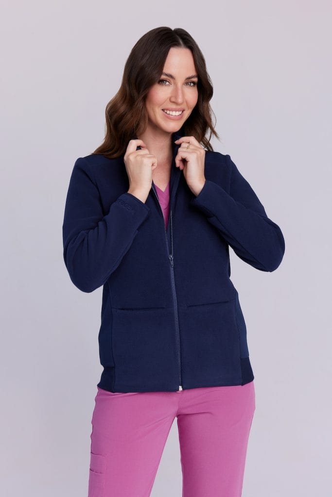 Kobieta ubrana w granatową polarową bluzę medyczną oraz różowe spodnie medyczne.