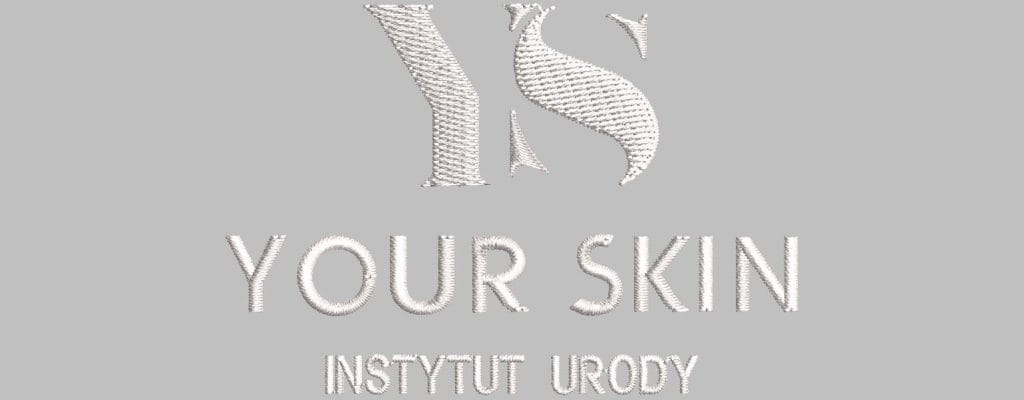 Logo Instytutu Urody Your Skin w haftowanym stylu na szarym tle
