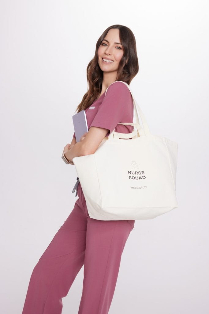 Nő rózsaszín orvosi egyenruhában, fehér ápolói táskával a vállán